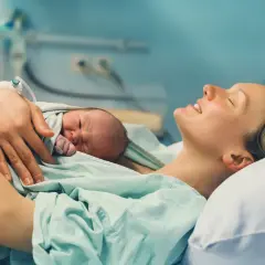Szczęśliwa mama tuli noworodka. To piękny czas połogu, pełen miłości i spokoju.