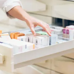 Dłoń sięga po leki w aptece, szukając odpowiedniego preparatu, być może antinal na problemy żołądkowe.