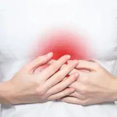 Dłonie obejmują brzuch, gdzie czerwony obszar symbolizuje ból w splocie słonecznym.
