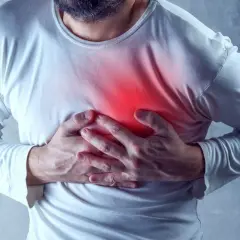 Mężczyzna trzyma się za klatkę piersiową, gdzie widoczny jest czerwony obszar bólu. Może to być jeden z objawów nadciśnienia.