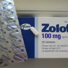 Opakowanie leku Zoloft 100 mg z sertraliną, obok blistra z tabletkami. Zoloft pomaga w leczeniu depresji.