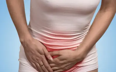 Kobieta trzyma ręce na brzuchu, gdzie widać zaczerwienienie. Odczuwa ból w pachwinie promieniujący na nogę.