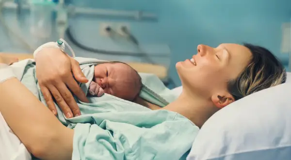 Szczęśliwa mama tuli noworodka. To piękny czas połogu, pełen miłości i spokoju.