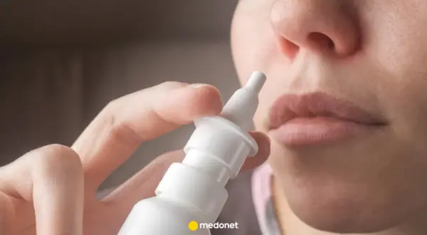 Dłoń trzymająca atomizer leku Avamys, gotowa do aplikacji do nosa.