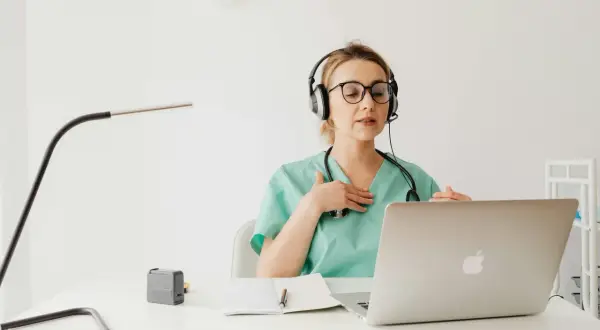 Lekarka w słuchawkach z mikrofonem wyjaśnia pacjentowi przez internet, jak stosować antybiotyk 3 dniowy.