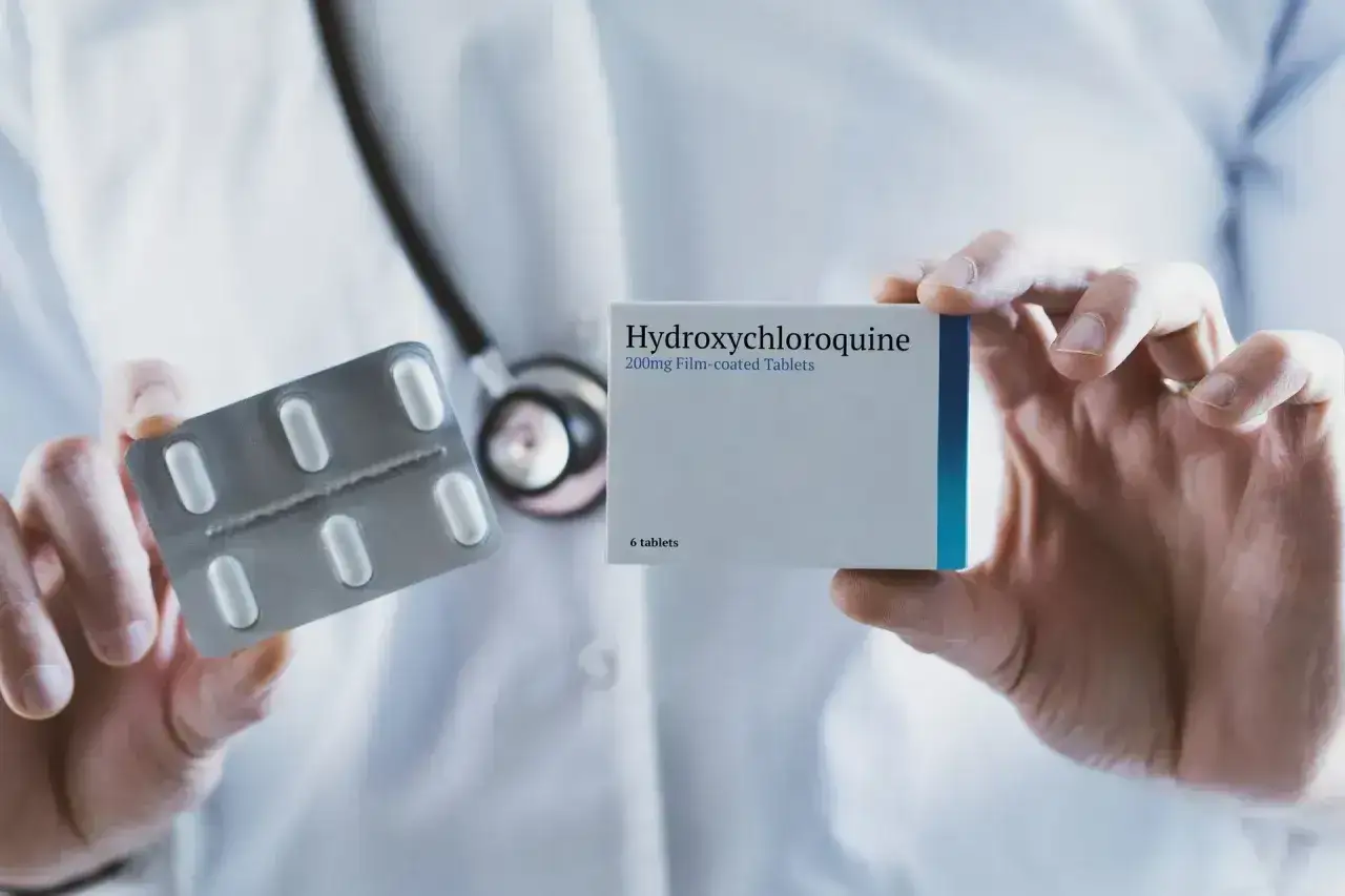 Lekarz prezentuje opakowanie i blister z tabletkami Hydroxychloroquine Adamed.