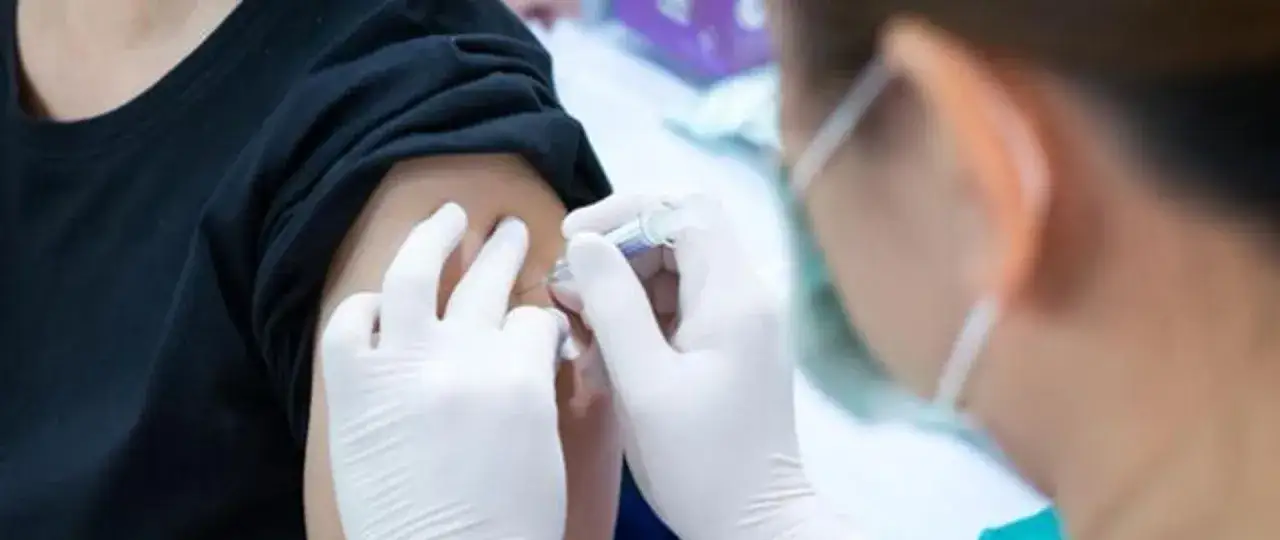 Ręce w białych rękawiczkach podają szczepionkę, chroniąc przed polio.