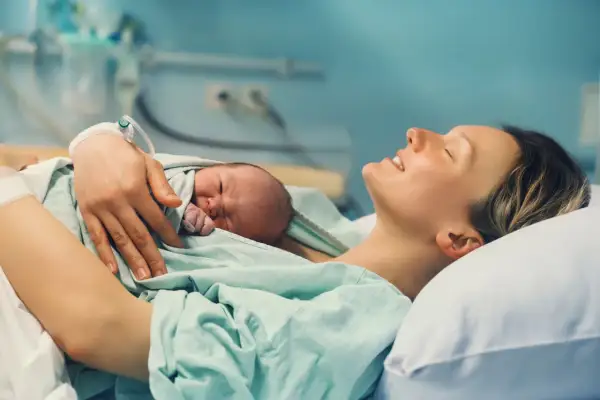 Szczęśliwa mama tuli noworodka. To piękny czas połogu, pełen miłości i spokoju.