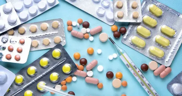 Różne tabletki i kapsułki, w tym te przypominające Diprolen, leżą obok termometru.