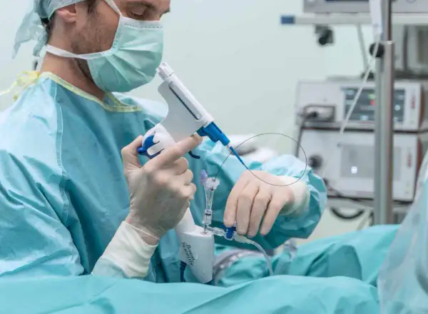 Chirurg w masce i rękawiczkach przygotowuje się do biopsji prostaty, trzymając specjalistyczny przyrząd.
