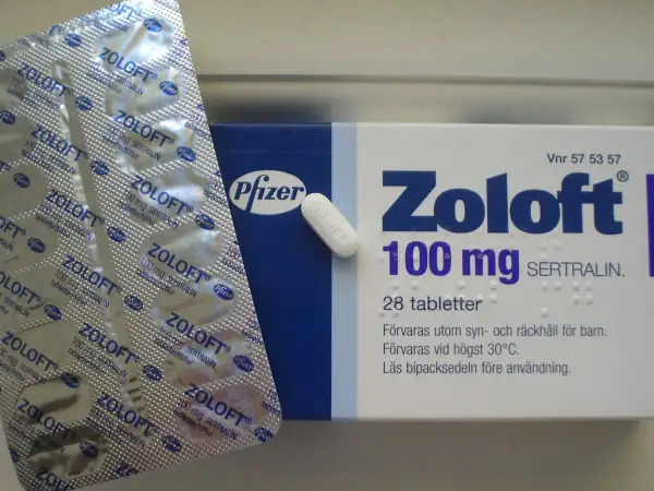 Opakowanie leku Zoloft 100 mg z sertraliną, obok blistra z tabletkami. Zoloft pomaga w leczeniu depresji.